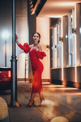 a glamorous woman in a red dress posing in the city