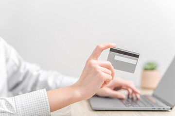 Woman using laptop and holding credit card in hands.