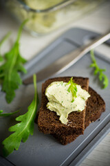 bread cheese spread with garlic and arugula on dark bread
