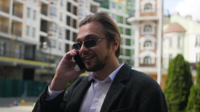 Good-looking successful adult man finishes phone call and celebrates good news. Caucasian guy is told about career raise at work and expresses his happiness. Attractive businessman celebrates success
