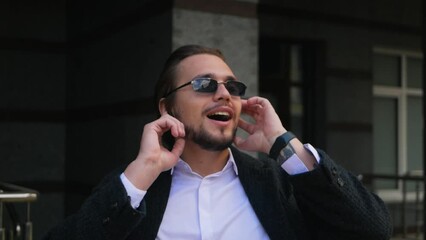 Attractive caucasian man listening to music on earphones and singing along. Cheerful successful guy grooving to music and singing chorus to favorite song. Rich adult moving to rhythm in headphones
