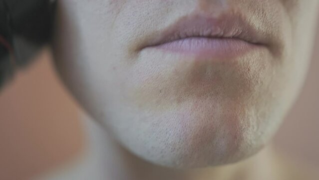 Macro front view of a young man who is shaving his chin.