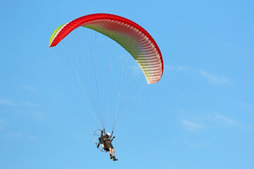 Paramotor pilot flying in a blue sky	