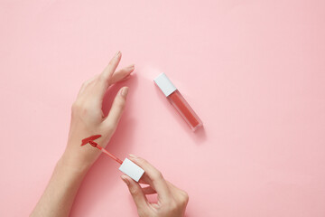 Top view of hand model using lipstick on hand in pink background for cosmetic advertising	