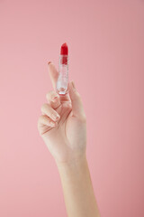 Top view of hand model using lipstick on hand in pink background for cosmetic advertising	