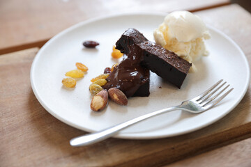 Brownies with dried fruits and ice cream on wood background