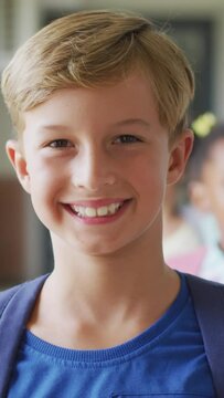 Video of happy caucasian boy standing at school corridor