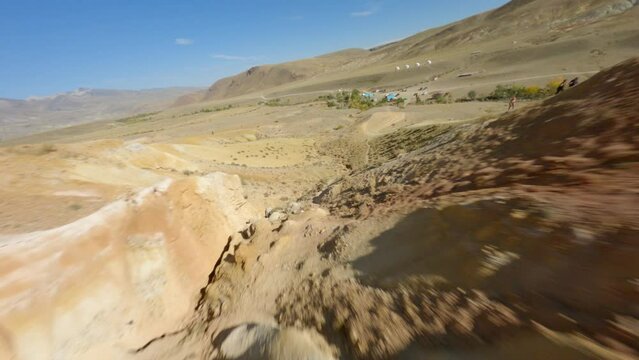 FPV sports drone shot destruction mountain dry cracked texture touristic natural landscape follow male photographer. Aerial view man tourist taking photo geology formation desert environment scenery