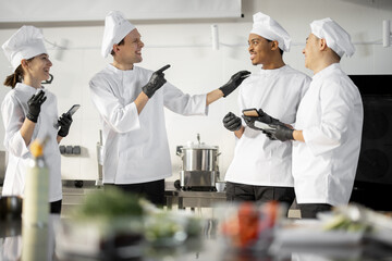 Team of multiracial cooks having conversation during a coffee break in the kitchen. Well-dressed chefs resting and having fun in the restaurant kitchen. Teamwork and leisure time on work