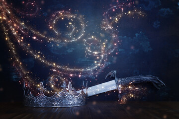 low key image of beautiful queen or king crown next to sword. fantasy medieval period. Selective focus © tomertu
