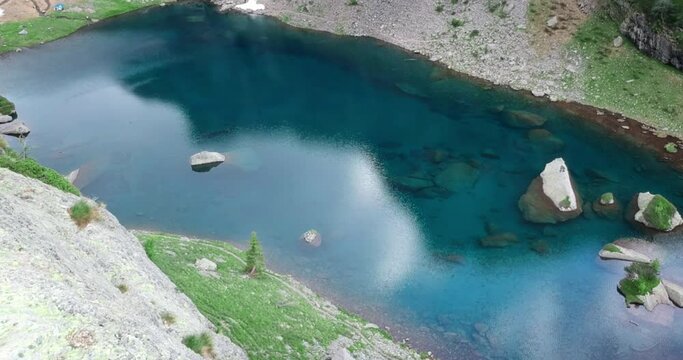 Drone shot of a young photographer takes a picture of a beautiful lake in the Italian alps from a high place