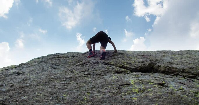 A young guy is climbing on a big rock looking for the sun