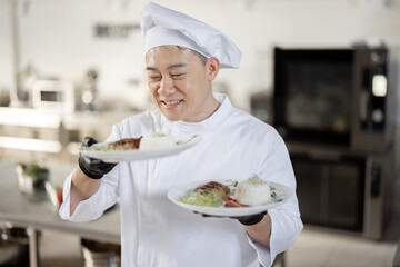 Portrait of young happy handsome smiling chef in uniform standing with ready meal in the kitchen....