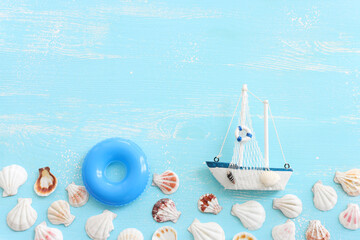 nautical concept with white sail boat and seashells over blue wooden background