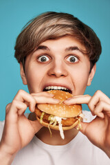 Very hungry young man holding tasty hamburger