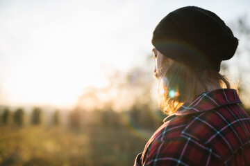 Young lumberjack standing in the field at sunset