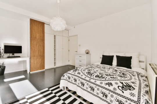 Spacious bedroom with comfy bed closet and workspace in daylight