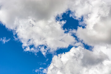Bright blue sky with white fluffy clouds, for use as an abstract background and textures.