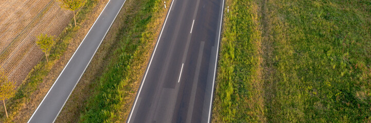 Panoramic image. Empty asphalt road and bike lane between fields from above
