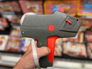 Retail store hand holding manual pricing gun side view