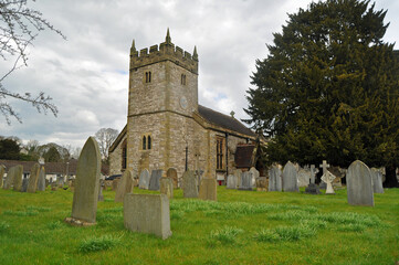 The pretty, typical Holy Trinity Church and churchyard with graves in picturesque Ashford In The Water Derbyshire U.K.