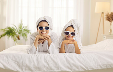Portrait of happy good looking mother and pretty little daughter wearing trendy sunglasses and head...
