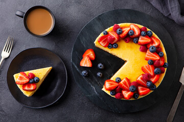 Cheesecake dessert with fresh berries and cup of coffee. Gray background. Close up. Top view.