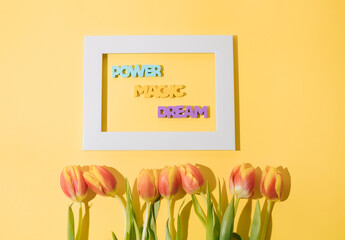 Motivating message in copy space and tulips on a yellow background. Top view