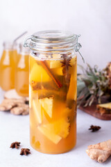 Tepache drink in glass bottles with reusable drinking straws and glass pitcher on kitchen table