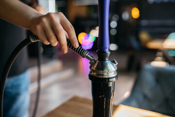 Hookah, spark, hookah sparks. Young man smokes fragrant oriental hookah. The hookah maker holds the tube from the hookah.