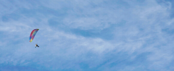 Unrecognizable adventure active extreme sports pilot flying in the sky with paramotor parachute engine. Paramotor flying in the sky at sunset.