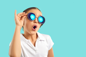 Funny teen child in summer glasses isolated on blue studio background look stunned and amazed. Cool...