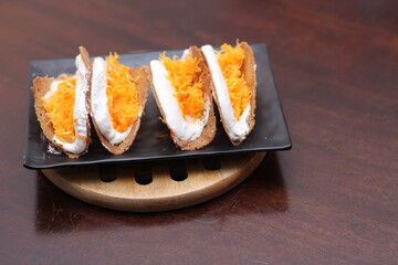 Thai Food, Thai Crispy Pancakes served in a black plate on a brown wooden table.