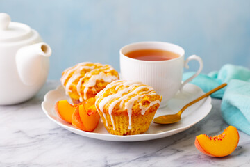 Peach cupcakes, muffins with cup of tea. Marble table. Close up.