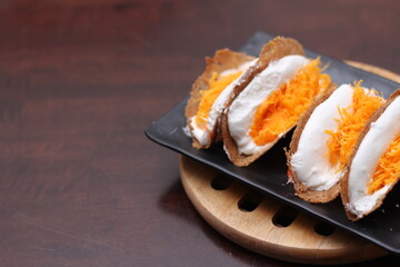Thai Food, Thai Crispy Pancakes served in a black plate on a brown wooden table.
