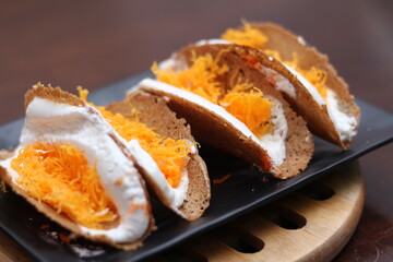 Thai Food, Thai Crispy Pancakes served in a black plate on a brown wooden table.