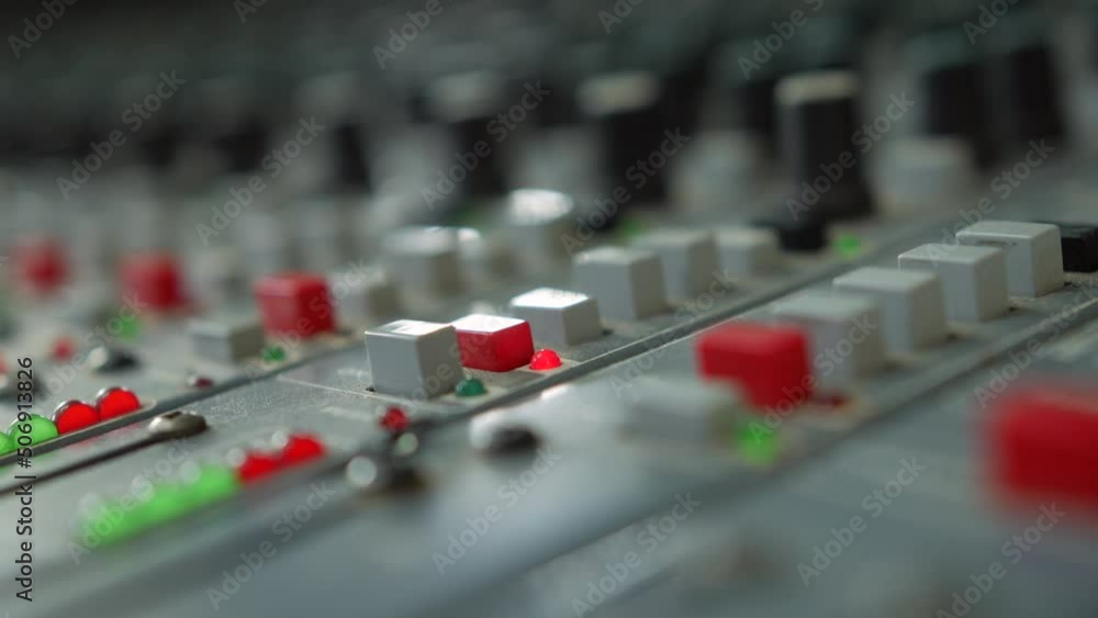 Poster pressing a button on a mixing desk console in a broadcast recording studio