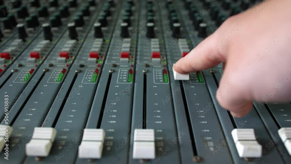 Poster close up of a music producer pushing up a fader on a mixing desk console