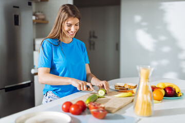 Young woman preparing salad in the kitchen