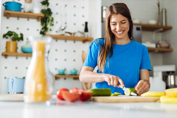 Young woman preparing salad in the kitchen