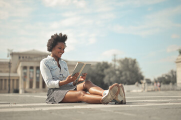 Fototapeta na wymiar happy woman is reading a book sitting on the street