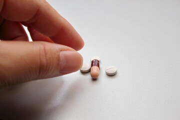 male hand picking up pills, capsules and tablets