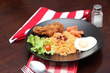 American fried rice served with sausages, cucumbers, shredded vegetables in a gray plate on a white table with seasoning.