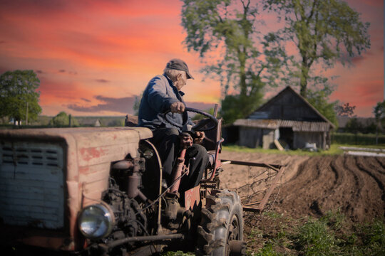 farmer on a tractor plows the soil in the garden, farming in the village. Old vintage tractor.