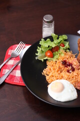 American fried rice served with sausages, cucumbers, shredded vegetables in a gray plate on a white table with seasoning.
