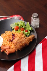 American fried rice served with sausages, cucumbers, shredded vegetables in a gray plate on a white table with seasoning.