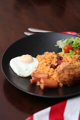 American fried rice served with sausages, cucumbers, shredded vegetables in a gray plate on a white table with seasoning.