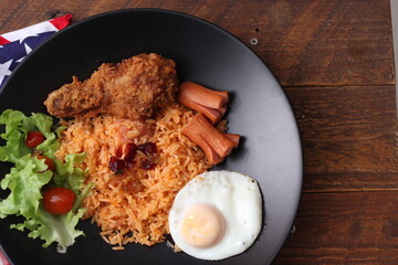 American fried rice served with sausages, cucumbers, shredded vegetables in a gray plate on a white table with seasoning.