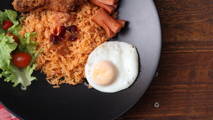 American fried rice served with sausages, cucumbers, shredded vegetables in a gray plate on a white table with seasoning.