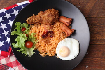 American fried rice served with sausages, cucumbers, shredded vegetables in a gray plate on a white table with seasoning.